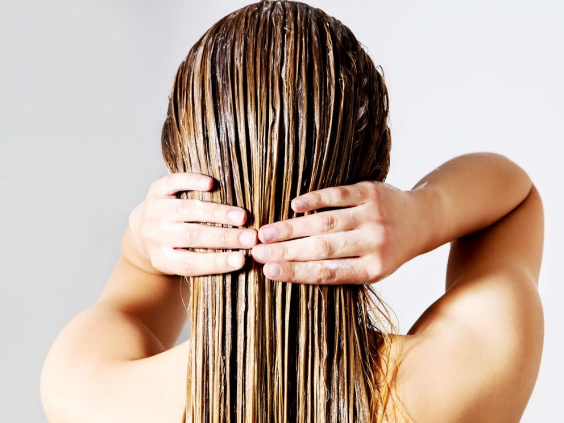Rear View Of Woman Applying Conditioner On Hair Against White Background