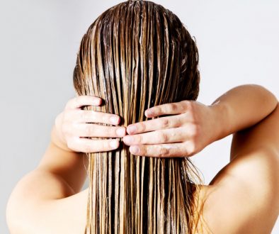 Rear View Of Woman Applying Conditioner On Hair Against White Background